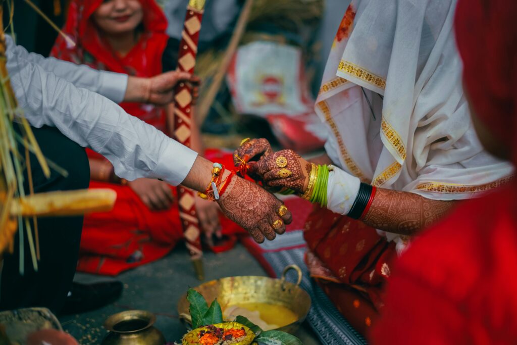 Close-up of a traditional Indian wedding ritual with colorful attire and henna designs.